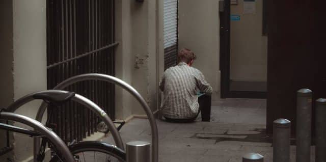 Man Sitting on the Sidewalk