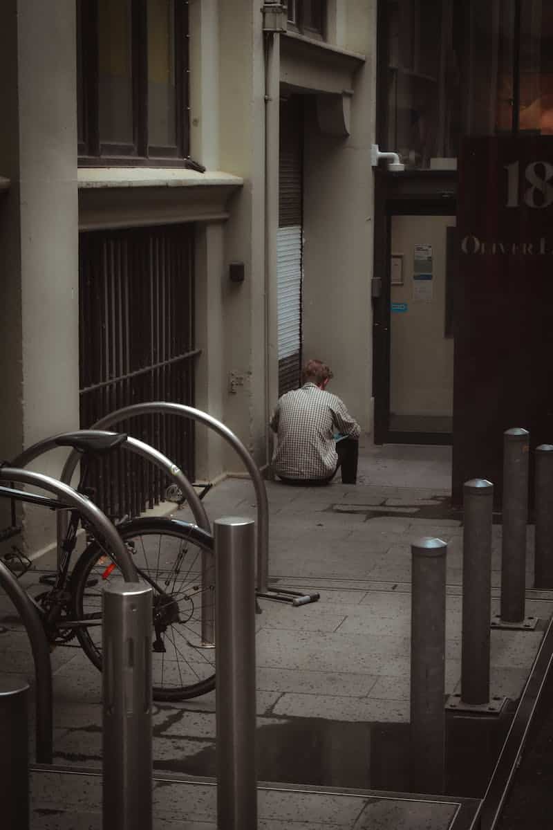 Man Sitting on the Sidewalk